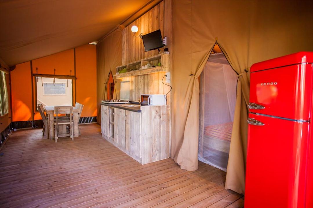 Interior of a glamping tent with kitchen and red fridge.