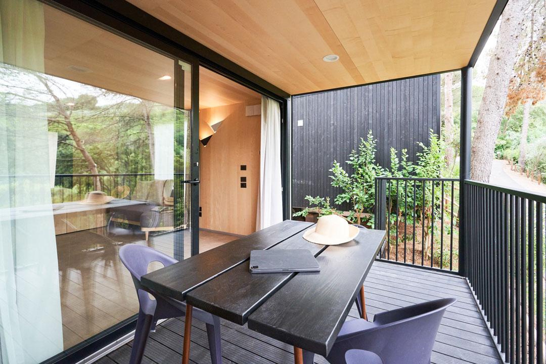 Modern terrace with table, chairs, and a view of greenery.