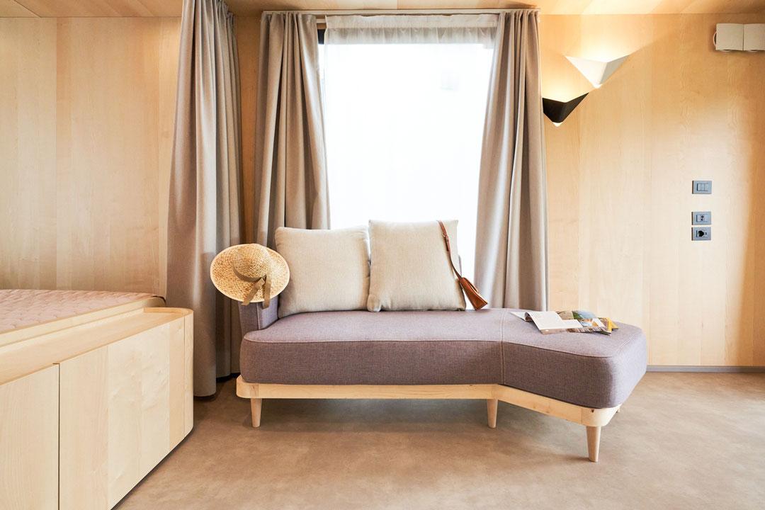 Salotto moderno con divano, cuscini e cappello di paglia.