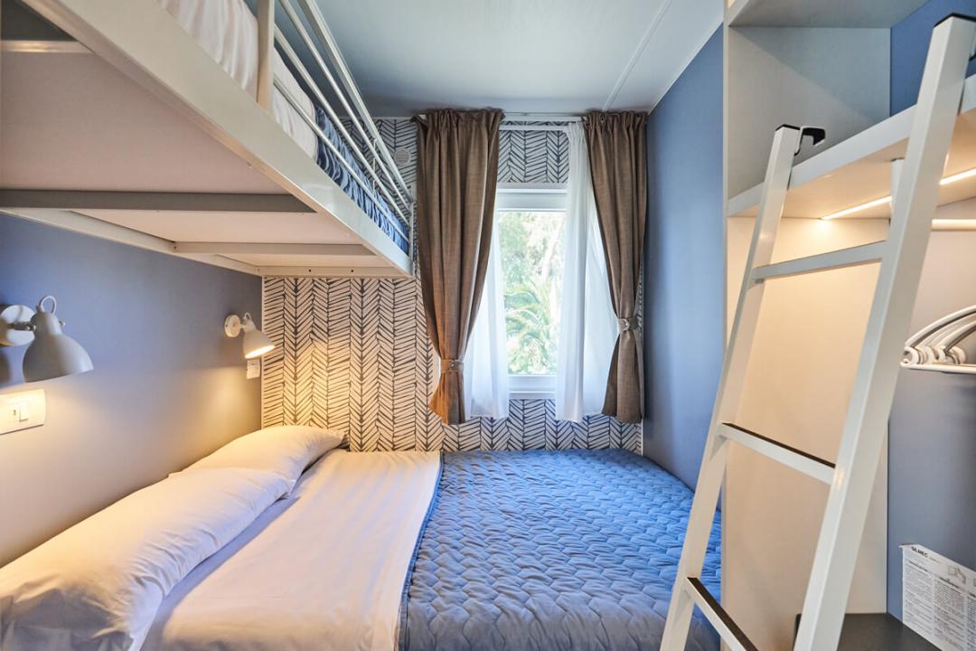Chambre avec lit double et lit superposé, décorée en bleu et blanc.