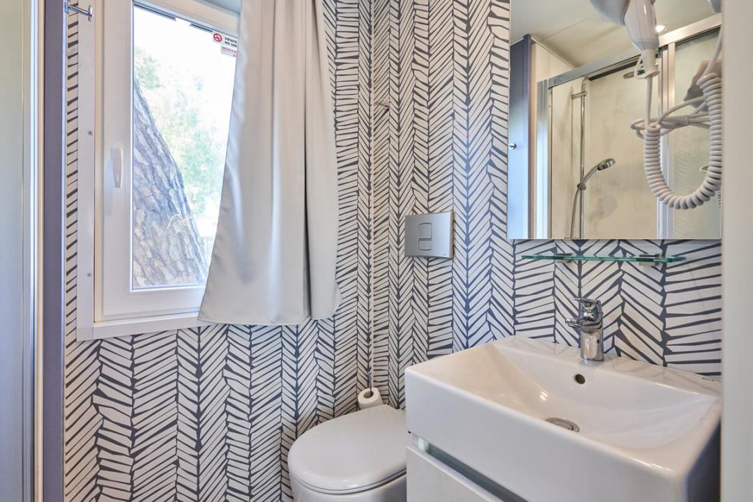 Salle de bain moderne avec fenêtre, lavabo, miroir et douche.