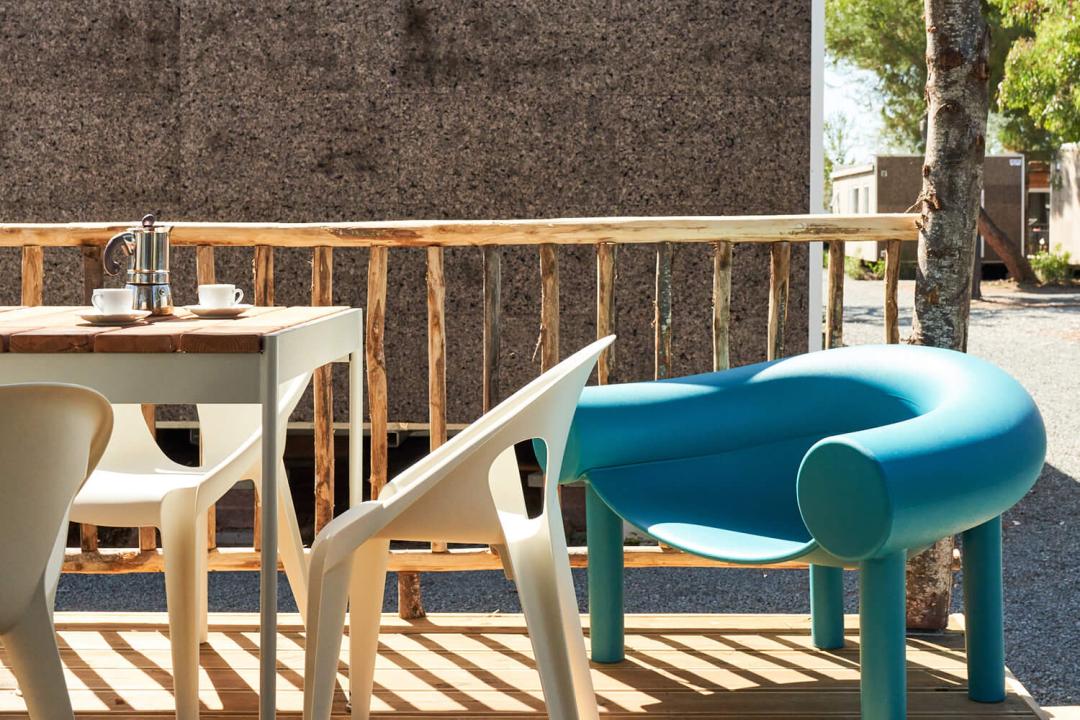 Terrasse avec chaises modernes et table, cafetière et tasses.
