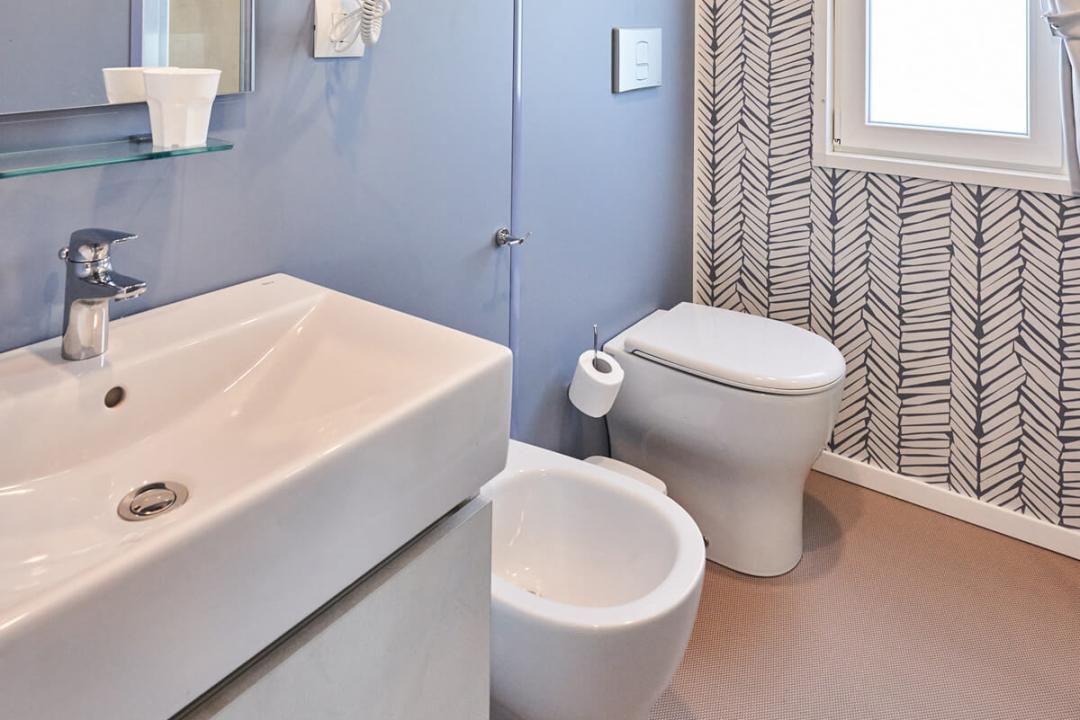 Salle de bain moderne avec bidet, lavabo, WC et sèche-cheveux.