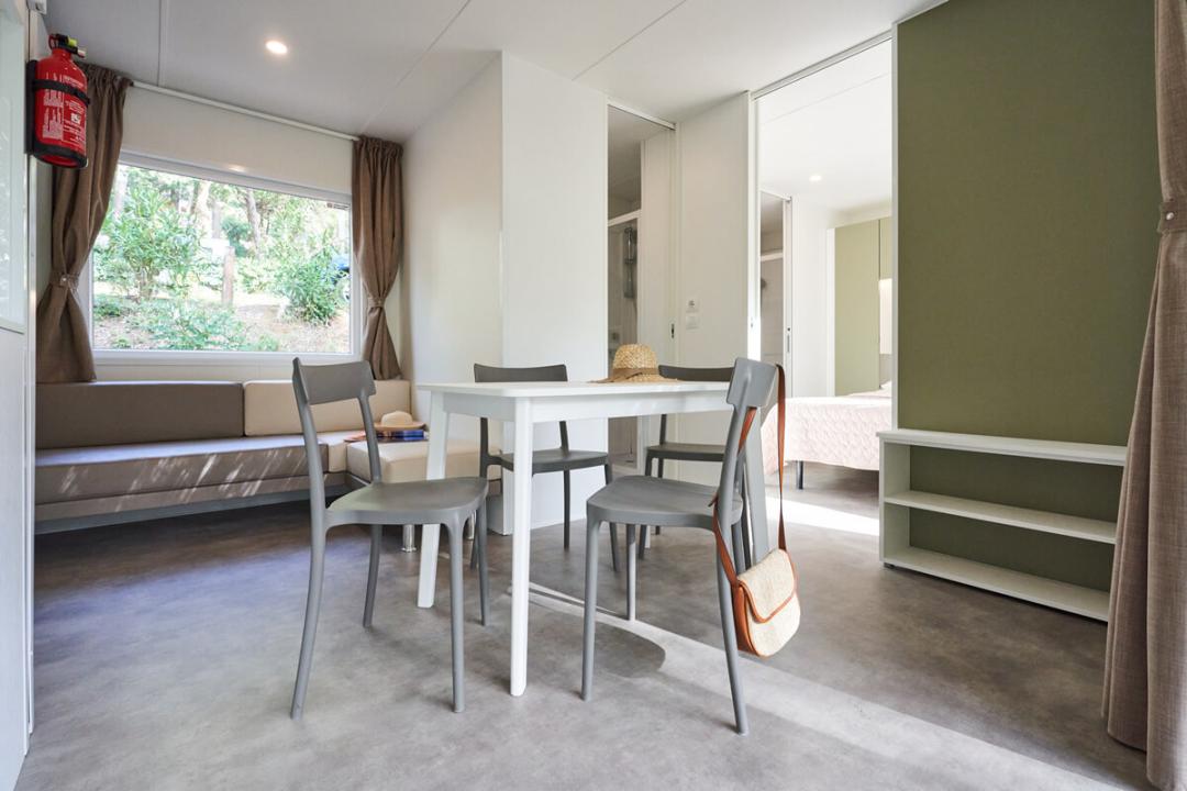 Moderne woonkamer met tafel, stoelen, bank en uitzicht op de tuin.