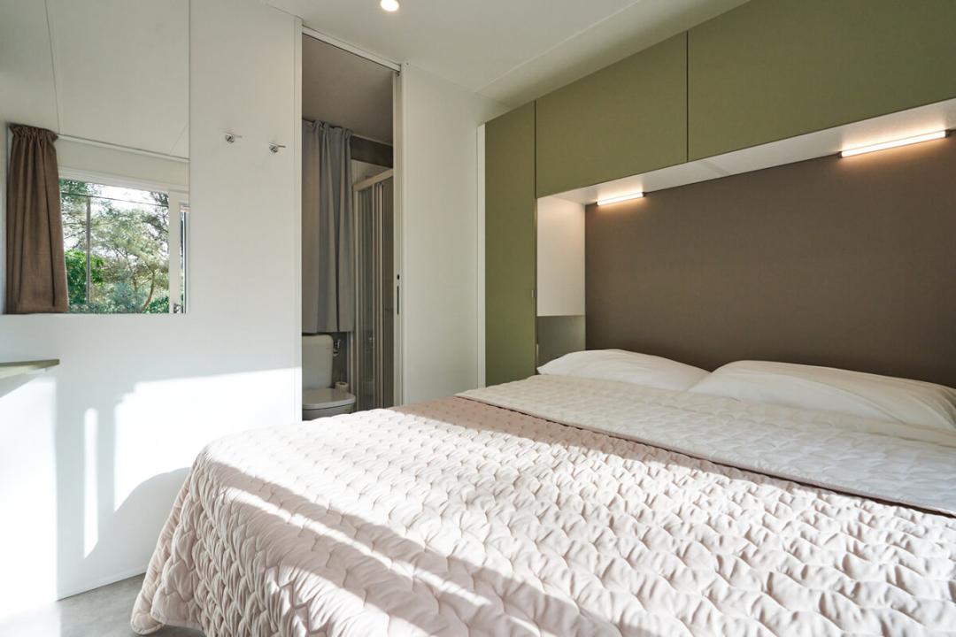 Nowoczesna sypialnia z łazienką i minimalistycznym wystrojem.
