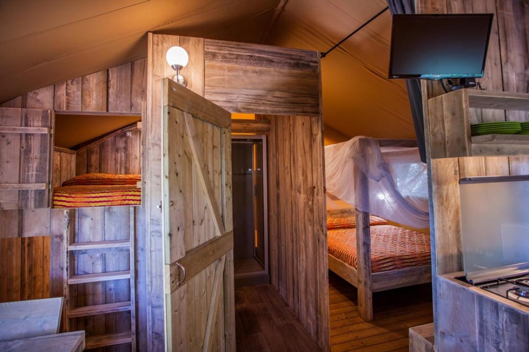 Przytulna drewniana kabina z łóżkami piętrowymi i podwójnym łóżkiem.