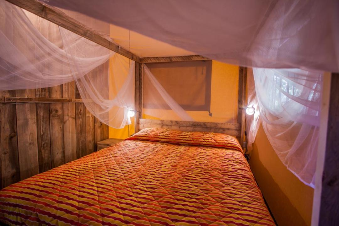 Rustykalny pokój z podwójnym łóżkiem i moskitierą.