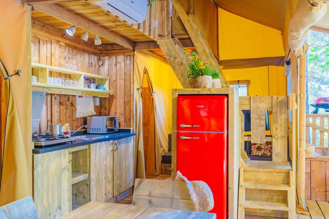 Cucina rustica con frigorifero rosso e scala in legno.