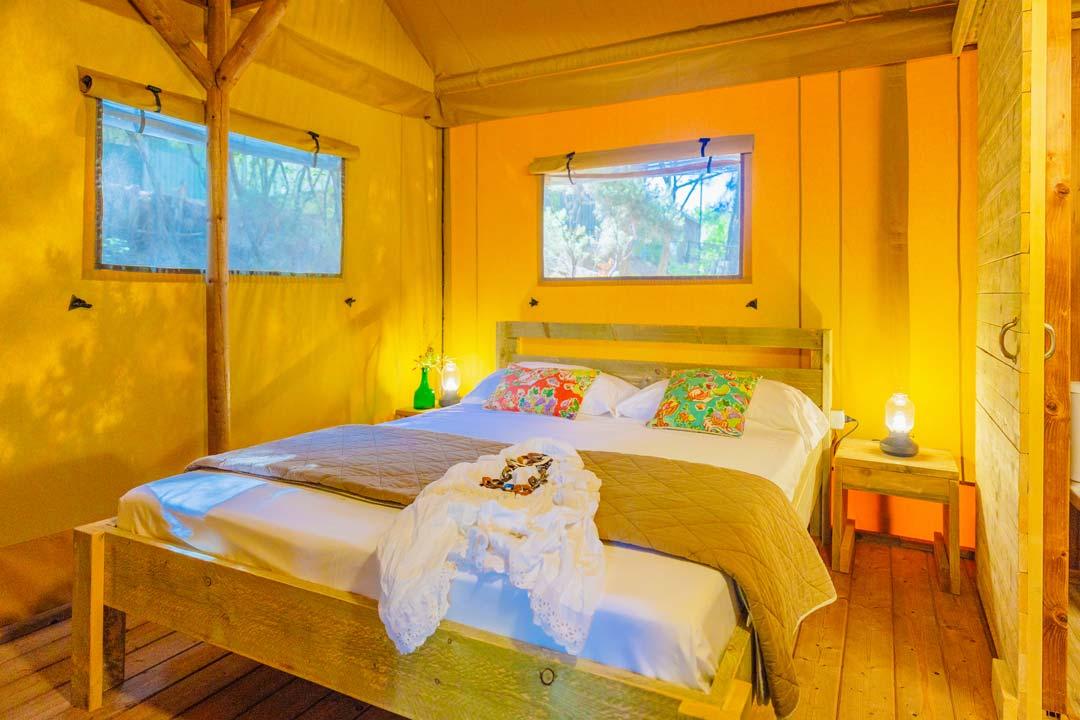 Gezellige kamer met een tweepersoonsbed en kleurrijke decoraties, verlicht door warm licht.