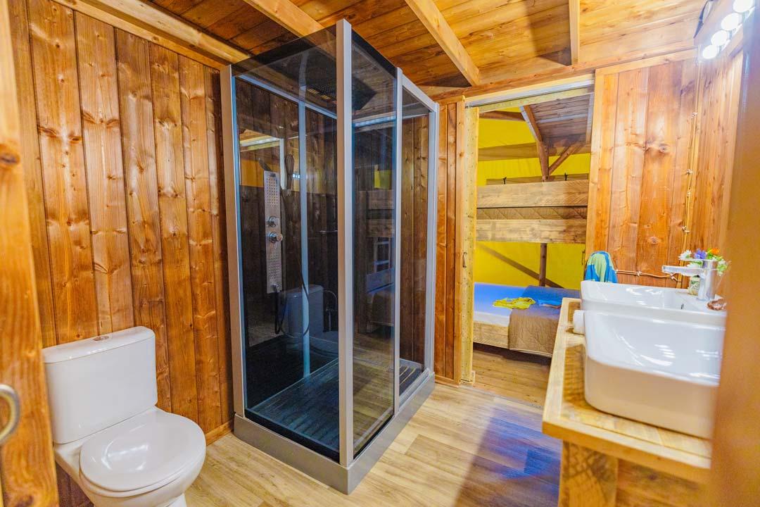 Houten badkamer met moderne douche en dubbele wastafel.