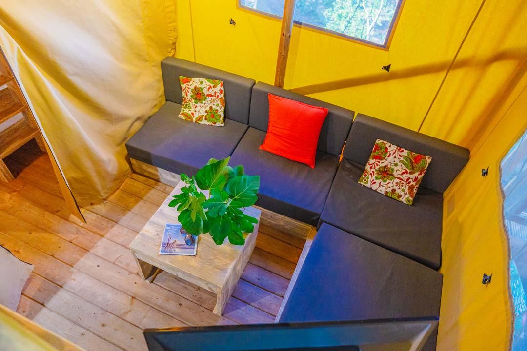 Salon confortable avec canapé d'angle, coussins colorés et plante décorative.