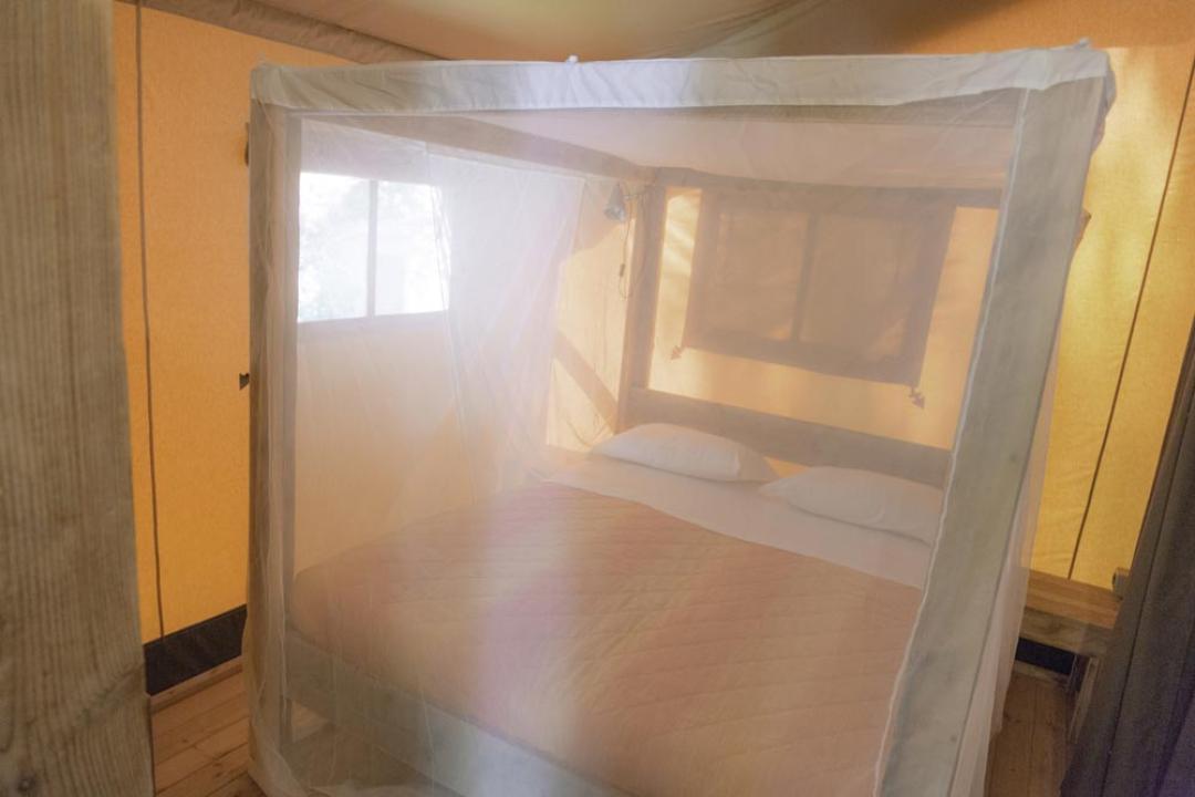 Łóżko z moskitierą w jasnym pokoju.